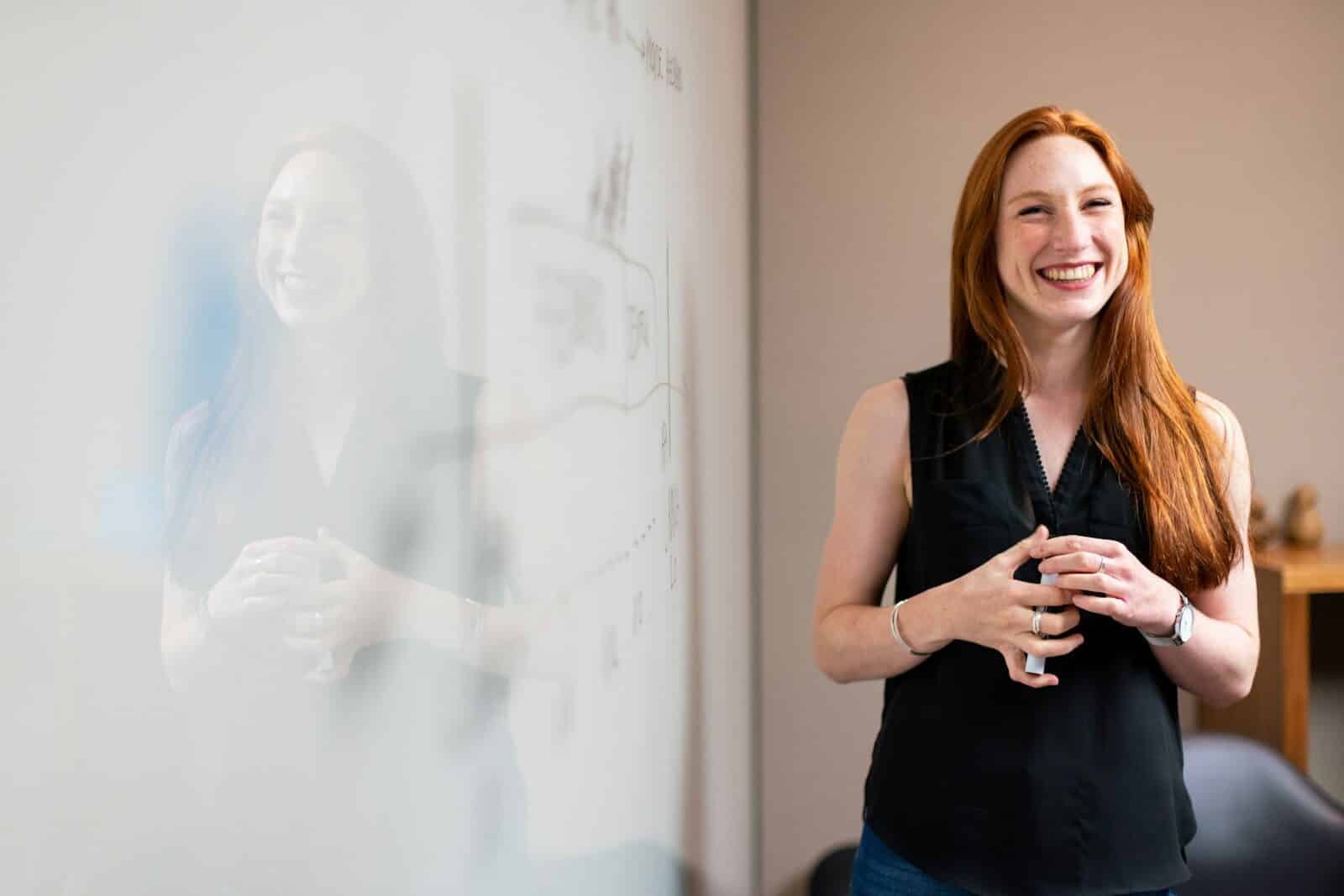 smiling woman presenting at whiteboard